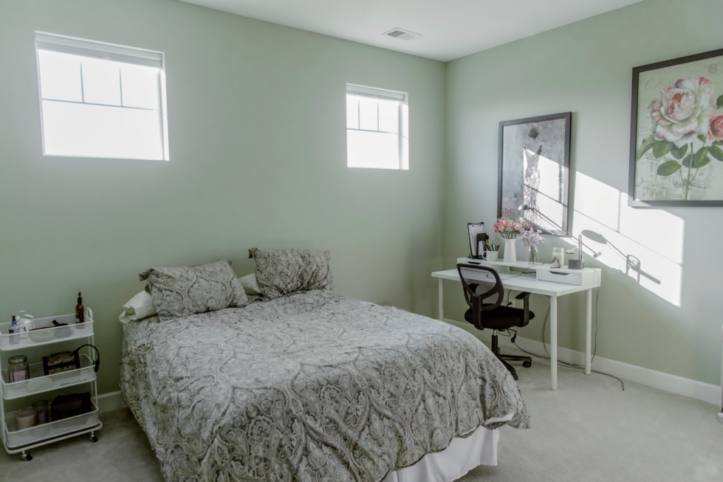 一间卧室，墙上有Farrow & Ball Cromarty的油漆，有床、桌子和墙壁装饰。