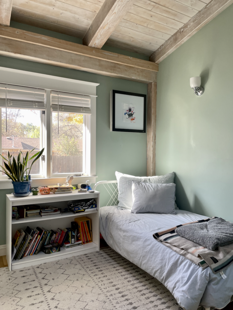 一间男孩卧室的天花板是木质的，刷的是绿蓝色的Farrow & Ball油漆，为整个房子的色调增添了美丽的色彩。